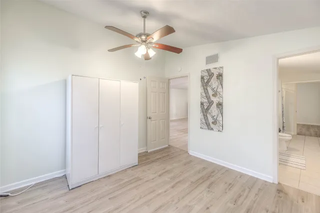 an empty room with wooden floor closet and fan