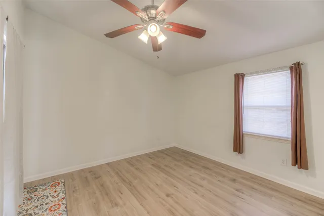 an empty room with a ceiling fan and wooden floor