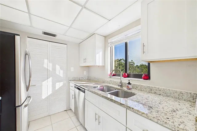 a kitchen with stainless steel appliances granite countertop a sink window and cabinets