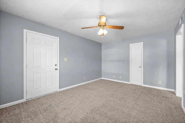 a view of an empty room with a chandelier fan