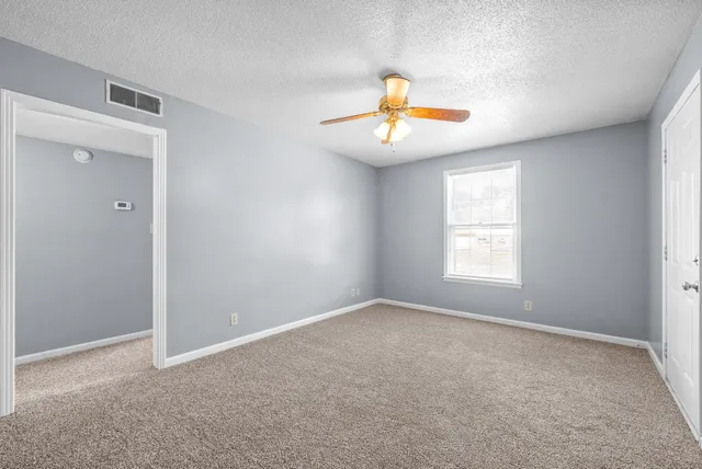 an empty room with windows and ceiling fan