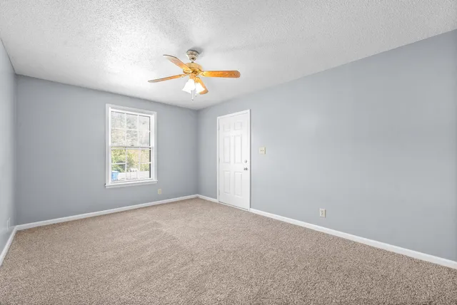 an empty room with windows and chandelier fan