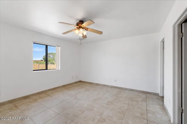 an empty room with windows and fan