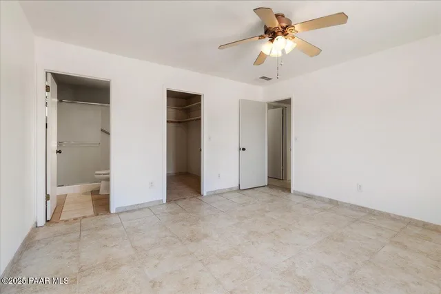 an empty room with closet and a chandelier fan
