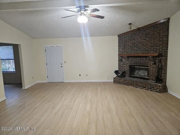 a view of empty room with wooden floor and fireplace