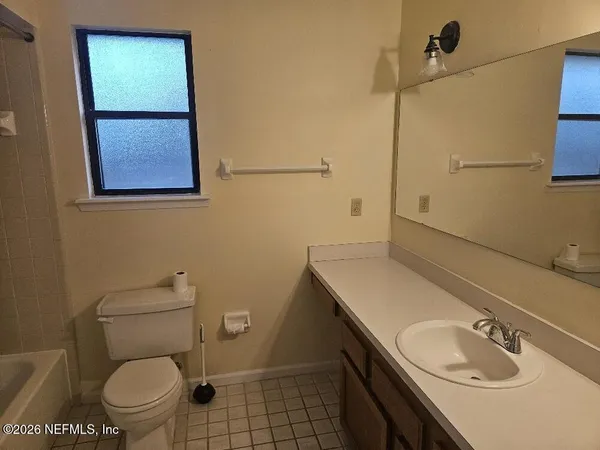 a bathroom with a granite countertop toilet sink and mirror