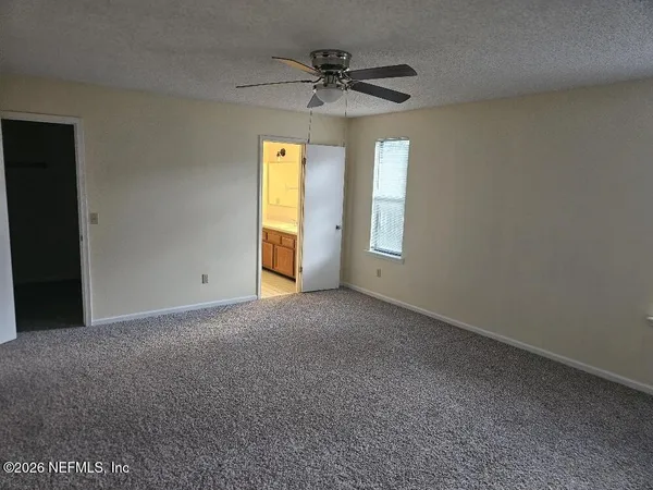 an empty room with a ceiling fan and window