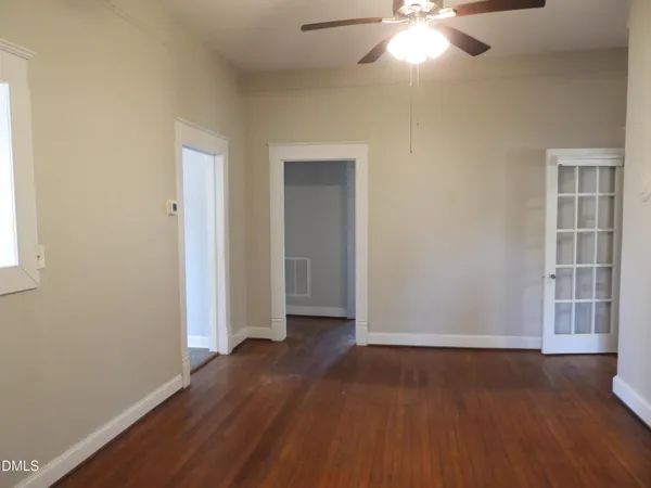 an empty room with wooden floor and windows