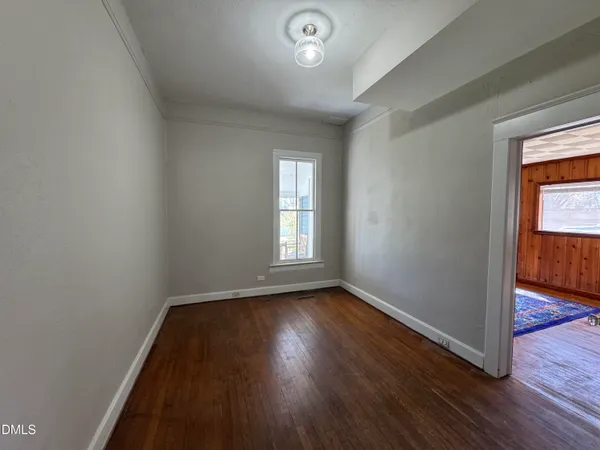 a view of an empty room with wooden floor and closet