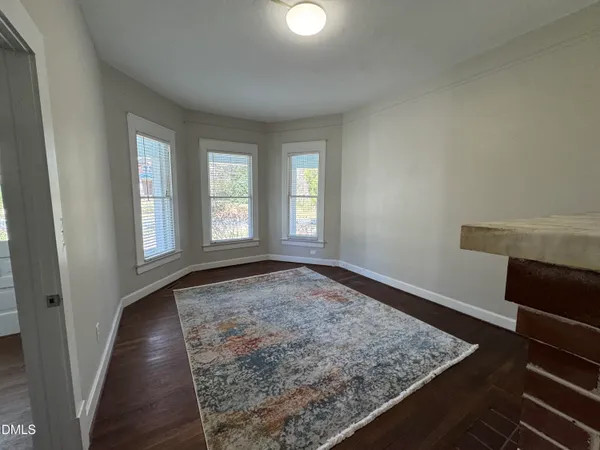 a view of an empty room with wooden floor and a ceiling fan