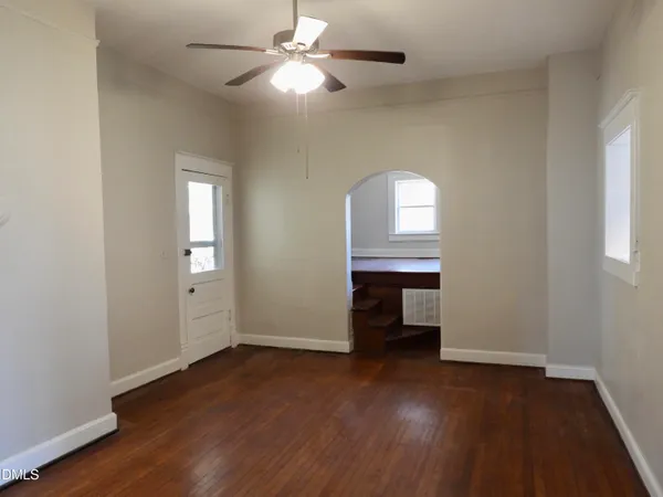 an empty room with wooden floor closet and windows