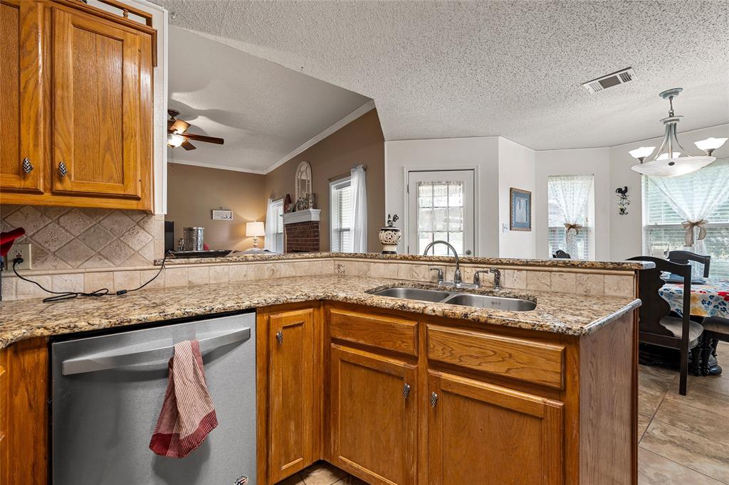 4617 Lexington Street Waco, TX 76705 - Photo 6 of 14 Kitchen featuring a double basin sink, granite-style countertops, wood cabinetry, stainless steel dishwasher, and tile backsplash