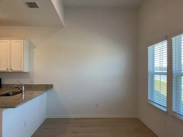 a view of a kitchen with granite countertop white cabinets and a wooden floor