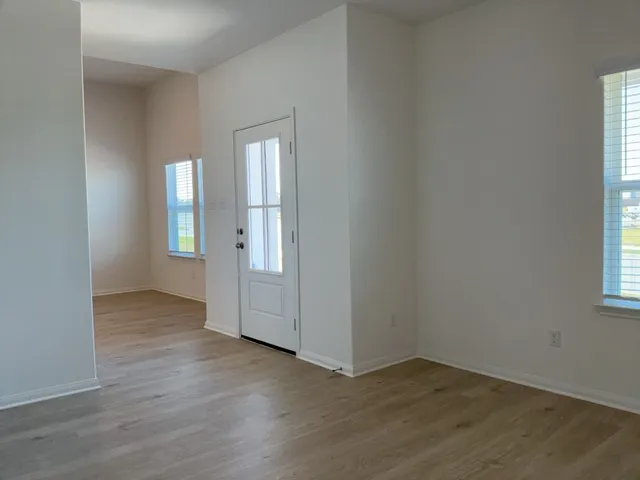 an empty room with wooden floor and windows