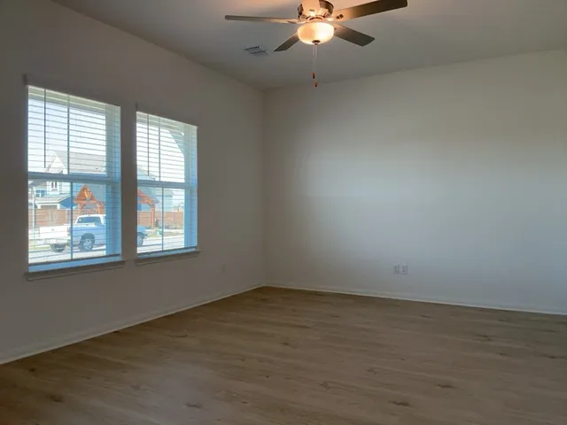 an empty room with wooden floor and windows