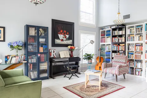 a living room with furniture a bookshelf and a window