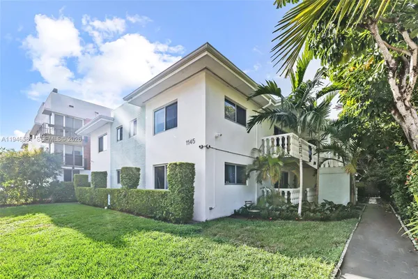 a view of a white house with a big yard and large trees