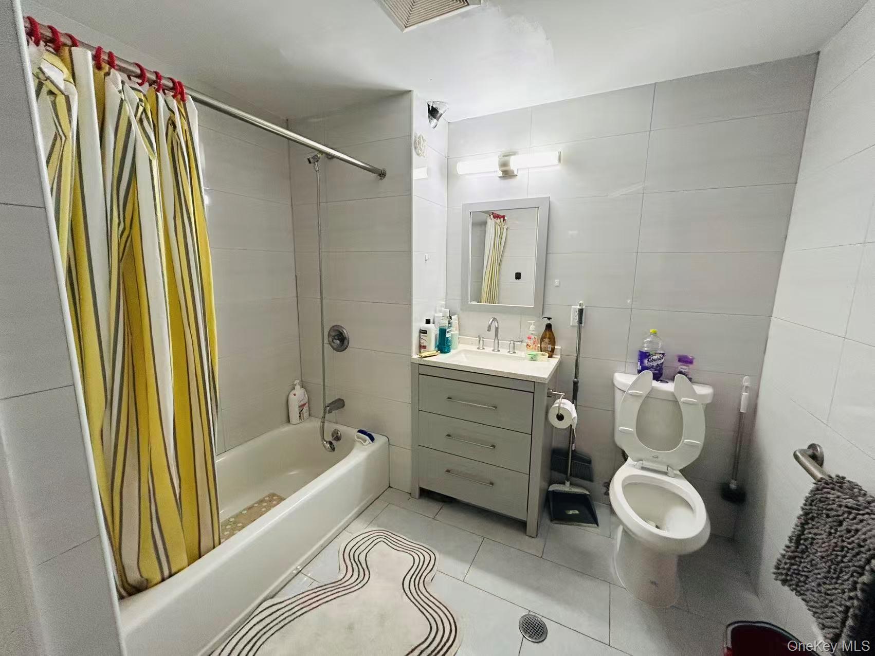 132-16 Maple Avenue, Unit 3A Queens, NY 11355 - Photo 9 of 10 a bathroom with a granite countertop sink toilet mirror vanity and bathtub
