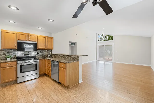 a kitchen with stainless steel appliances granite countertop a stove a sink and a refrigerator