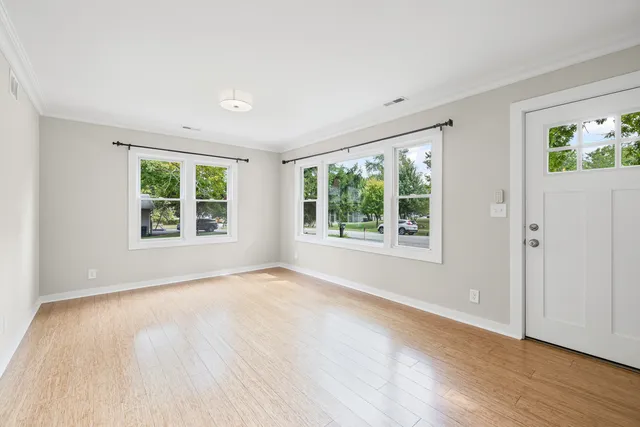 a view of an empty room with wooden floor and a window