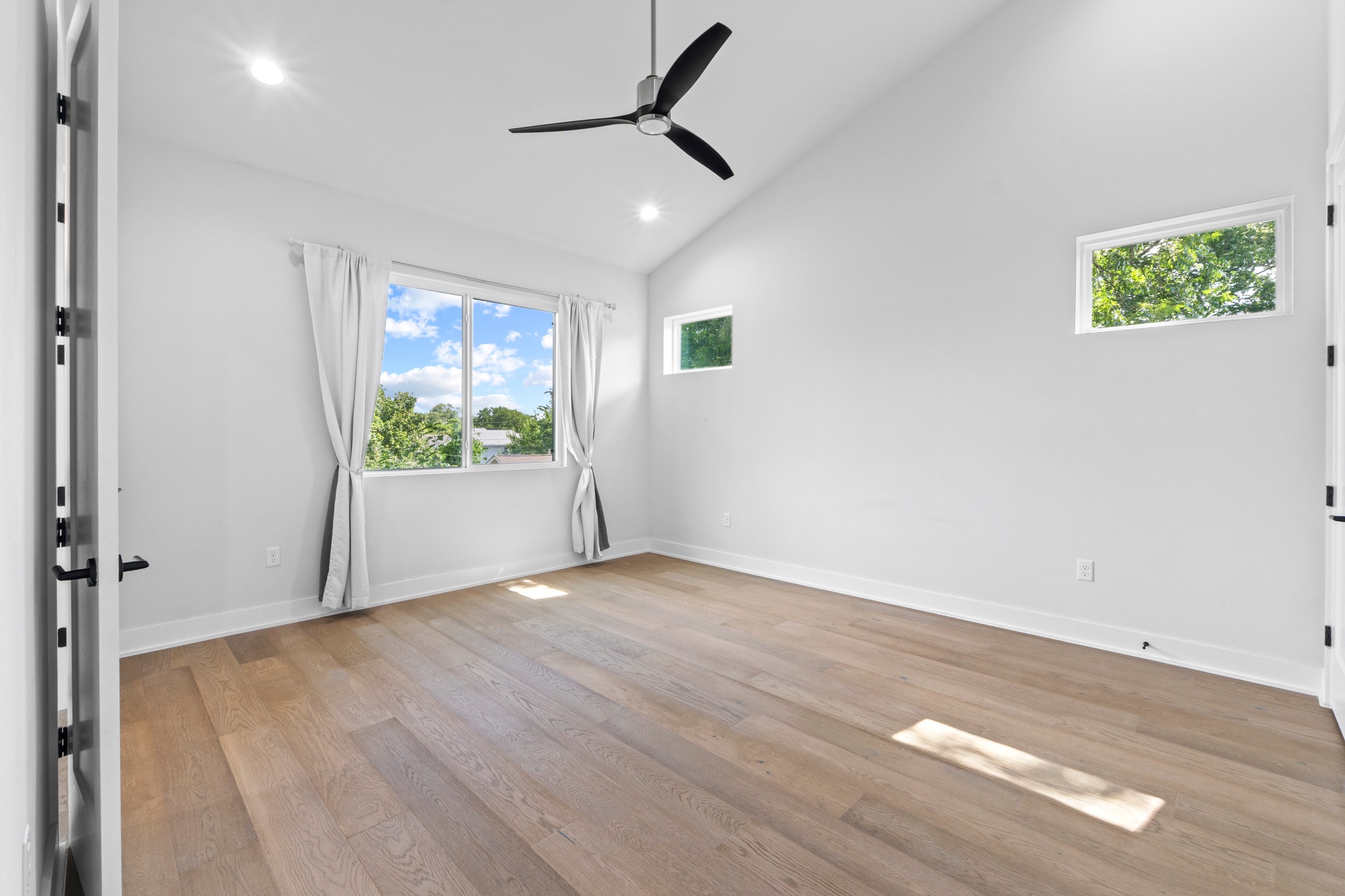 2007 Chestnut Avenue, Unit 1 Austin, TX 78722 - Photo 20 of 32 Natural light bathes this spacious bedroom, featuring high vaulted ceilings and durable hardwood flooring.