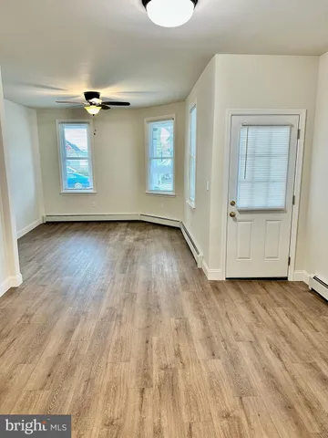 an empty room with wooden floor cabinet and windows