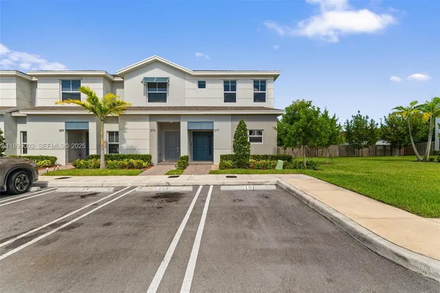 a view of a white house with a large space and a yard