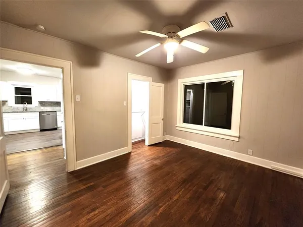 a view of an empty room with window and wooden floor