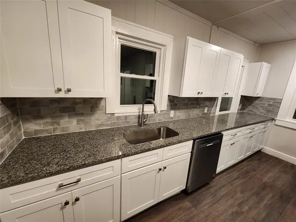 a kitchen with granite countertop white cabinets and sink
