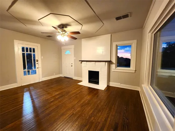 a view of a livingroom with a fireplace a ceiling fan and wooden floor