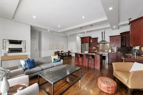 a living room with furniture kitchen view and a wooden floor