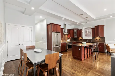 a kitchen with stainless steel appliances kitchen island granite countertop a dining table chairs and refrigerator