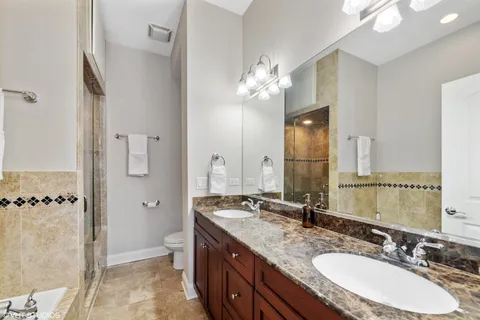 a bathroom with a granite countertop double vanity sink mirror double and shower