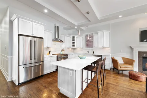 a kitchen with a refrigerator a stove a sink dishwasher and a dining table with wooden floor