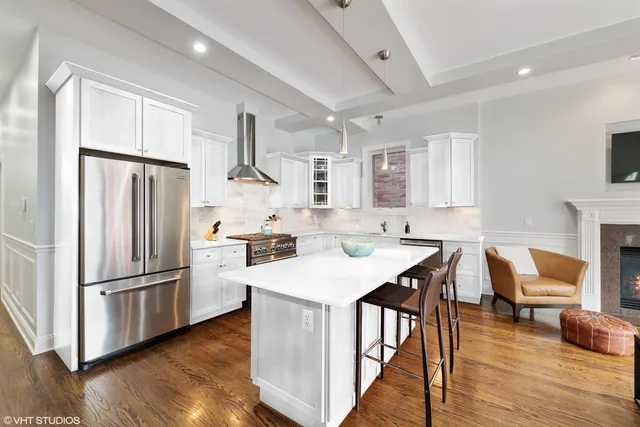 a kitchen with a refrigerator a stove a sink dishwasher and a dining table with wooden floor