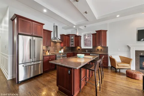 a kitchen with stainless steel appliances granite countertop a refrigerator a stove a sink a dining table and chairs with wooden floor