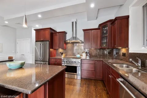 a kitchen with stainless steel appliances granite countertop a sink a stove and wooden cabinets