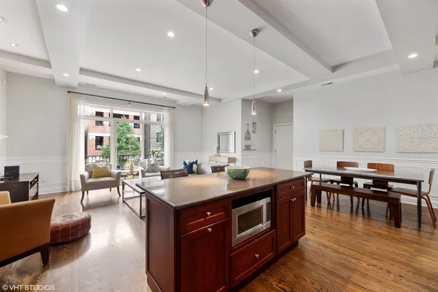 a kitchen with stainless steel appliances granite countertop a stove top oven a dining table and chairs with wooden floor