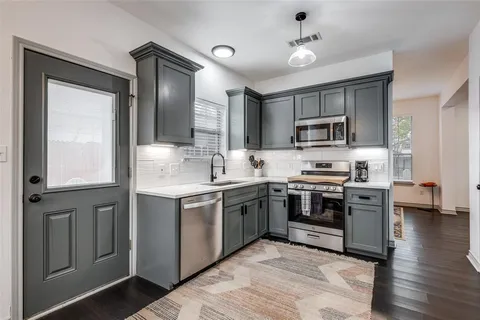 a kitchen with kitchen island granite countertop a sink cabinets and stainless steel appliances