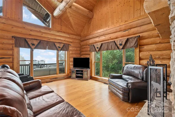 a living room with furniture a flat screen tv and floor to ceiling window