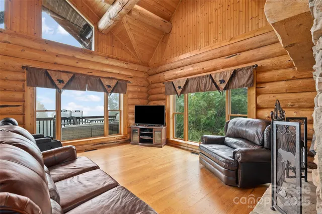 a living room with furniture a flat screen tv and floor to ceiling window