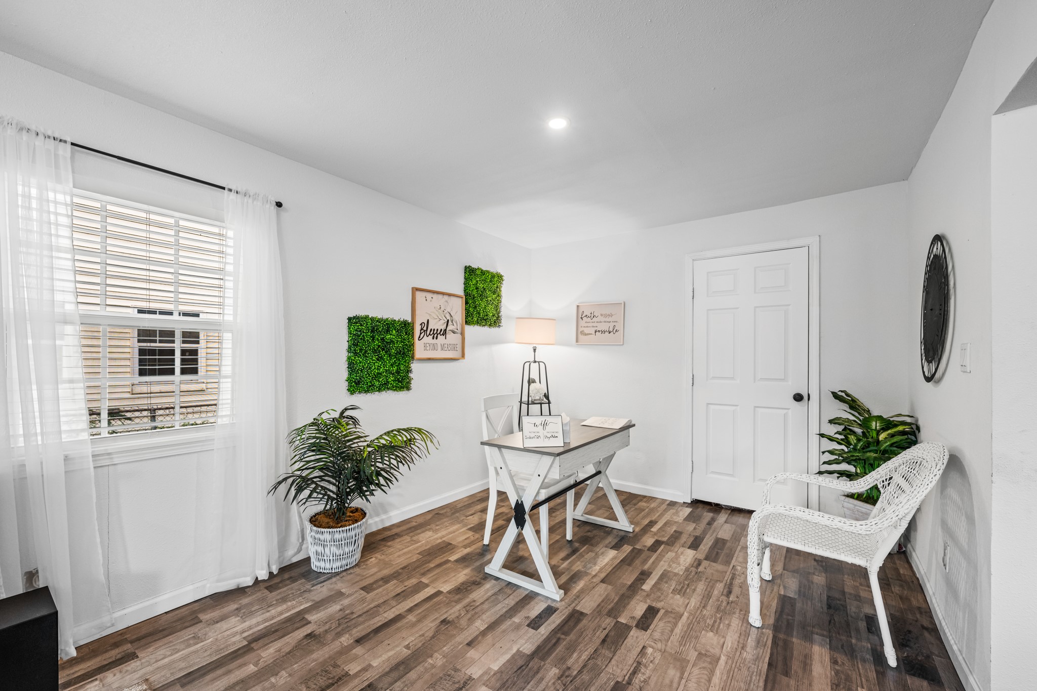 729 Kyle Angleton, TX 77515 - Photo 4 of 36 This office space is bright and inviting, featuring a modern desk, hardwood floors, and plenty of natural light. It's decorated with a greenery and wall art backdrop, making it perfect for a home office or study.