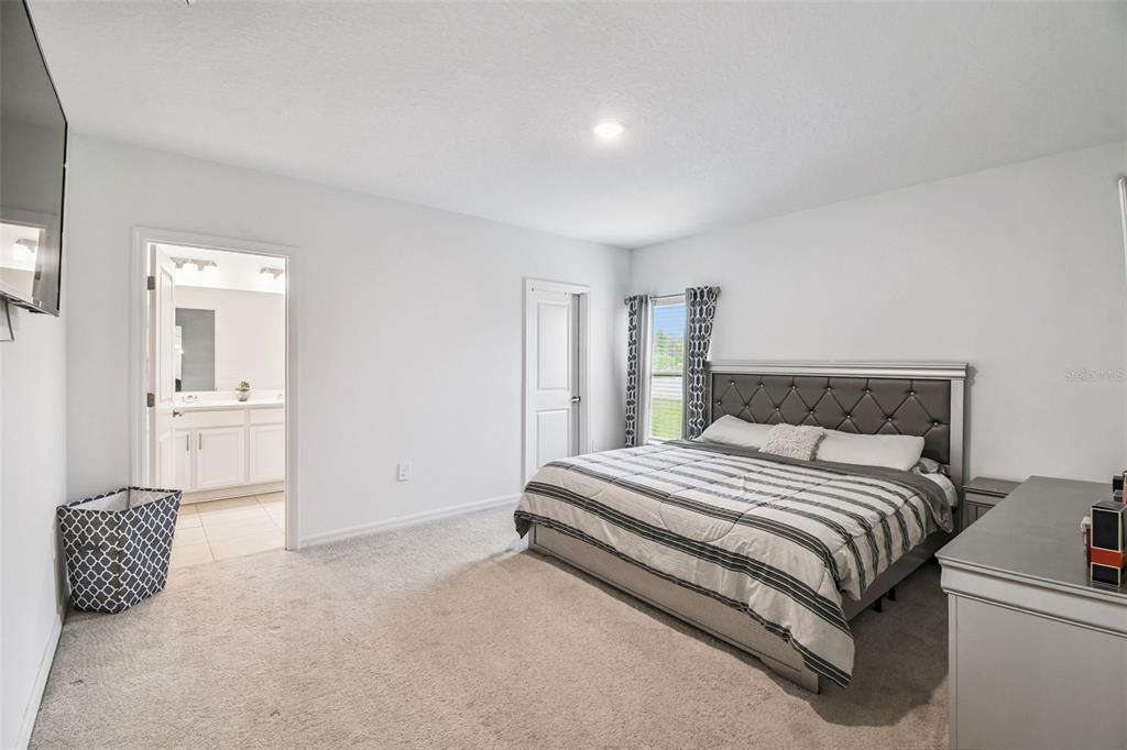 136 Citrine Loop Kissimmee, FL 34758 - Photo 20 of 28 a spacious bedroom with a bed and a view of bathroom
