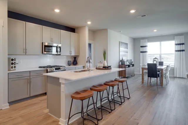 a kitchen with stainless steel appliances granite countertop a stove a sink a microwave a island with a dining table and chair