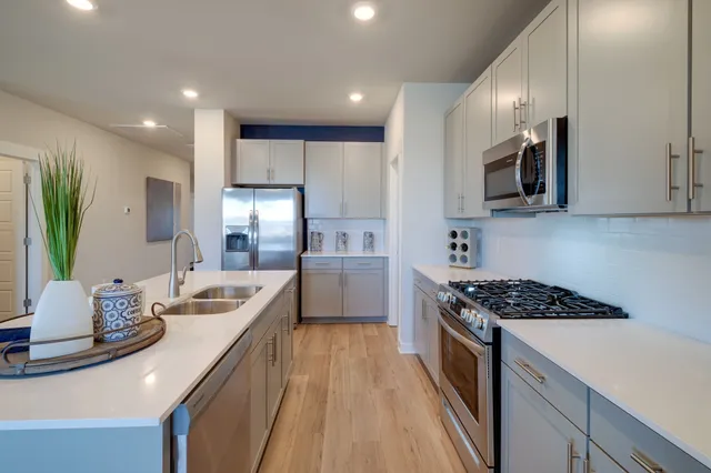 a kitchen with stainless steel appliances a sink a stove top oven a counter space and cabinets