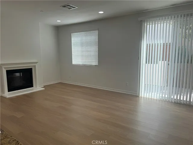 an empty room with wooden floor fireplace and windows