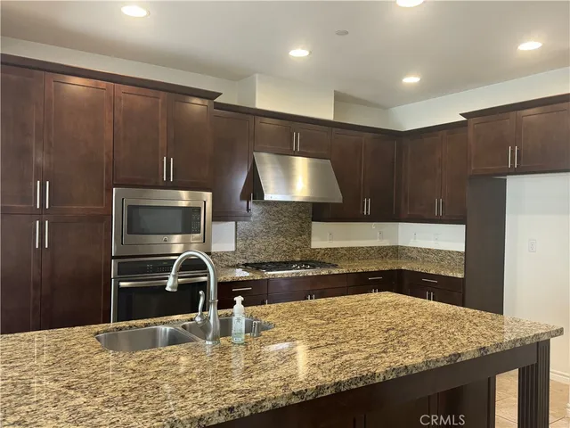 a kitchen with kitchen island granite countertop a sink stove and refrigerator