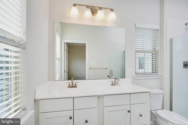 a bathroom with a granite countertop shower and a toilet