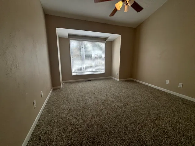 an empty room with a ceiling fan and window