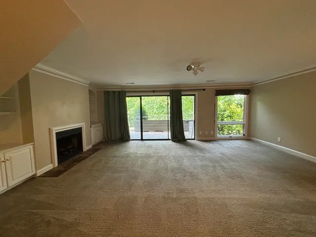 a view of an empty room with a fireplace and a window